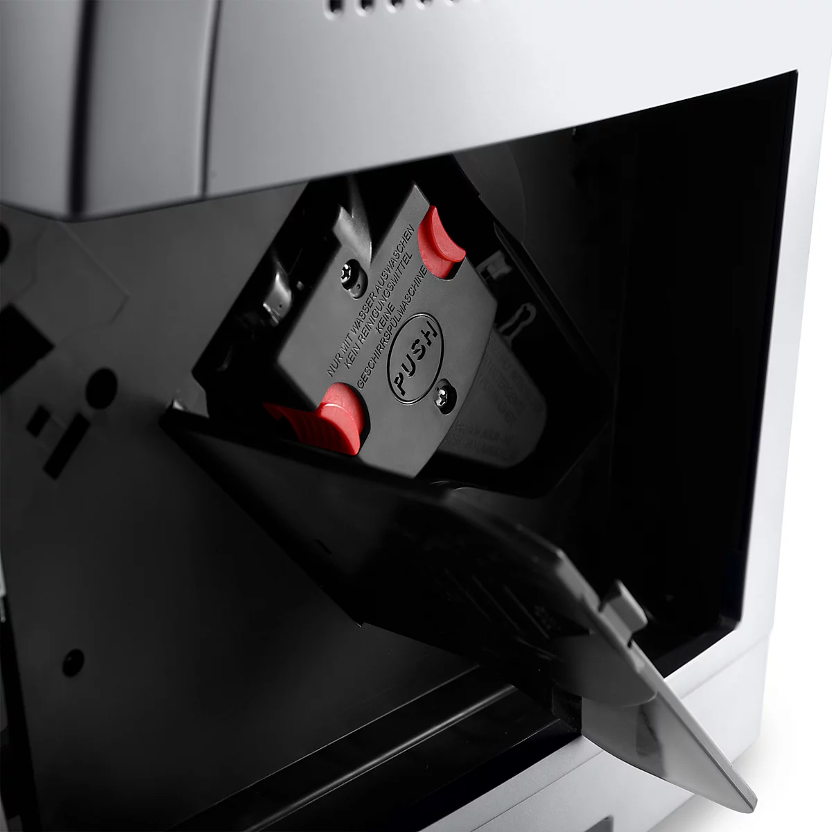 Detailopname van een koffiemachine. Zwarte klep met rode knop en "PUSH" label.