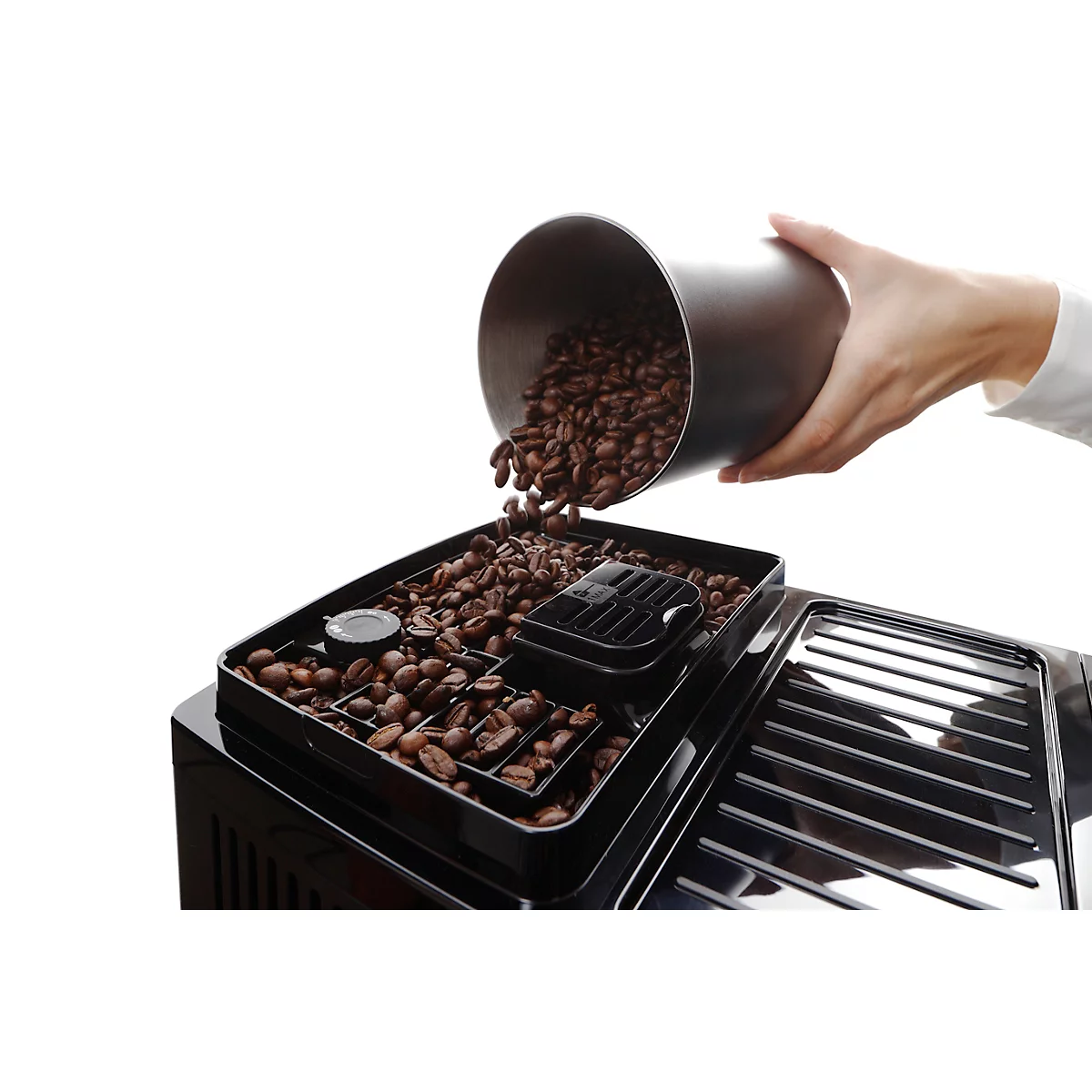 Een hand giet koffiebonen uit een zilveren container in een koffiemachine.