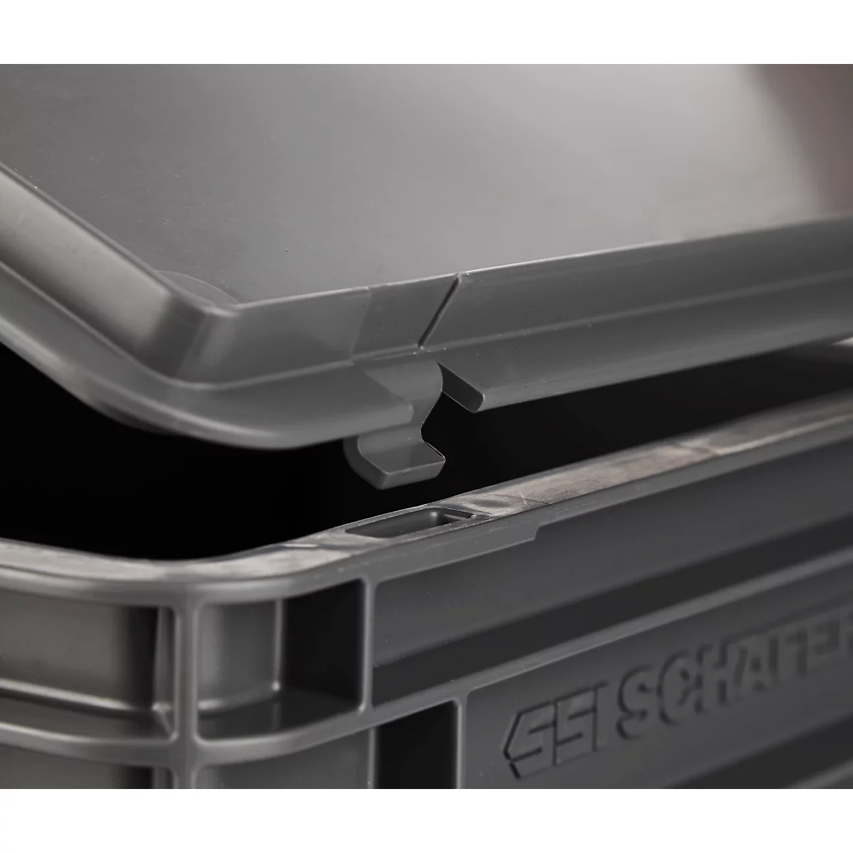 Grijze plastic krat, deksel half open, sluiting in detail getoond.