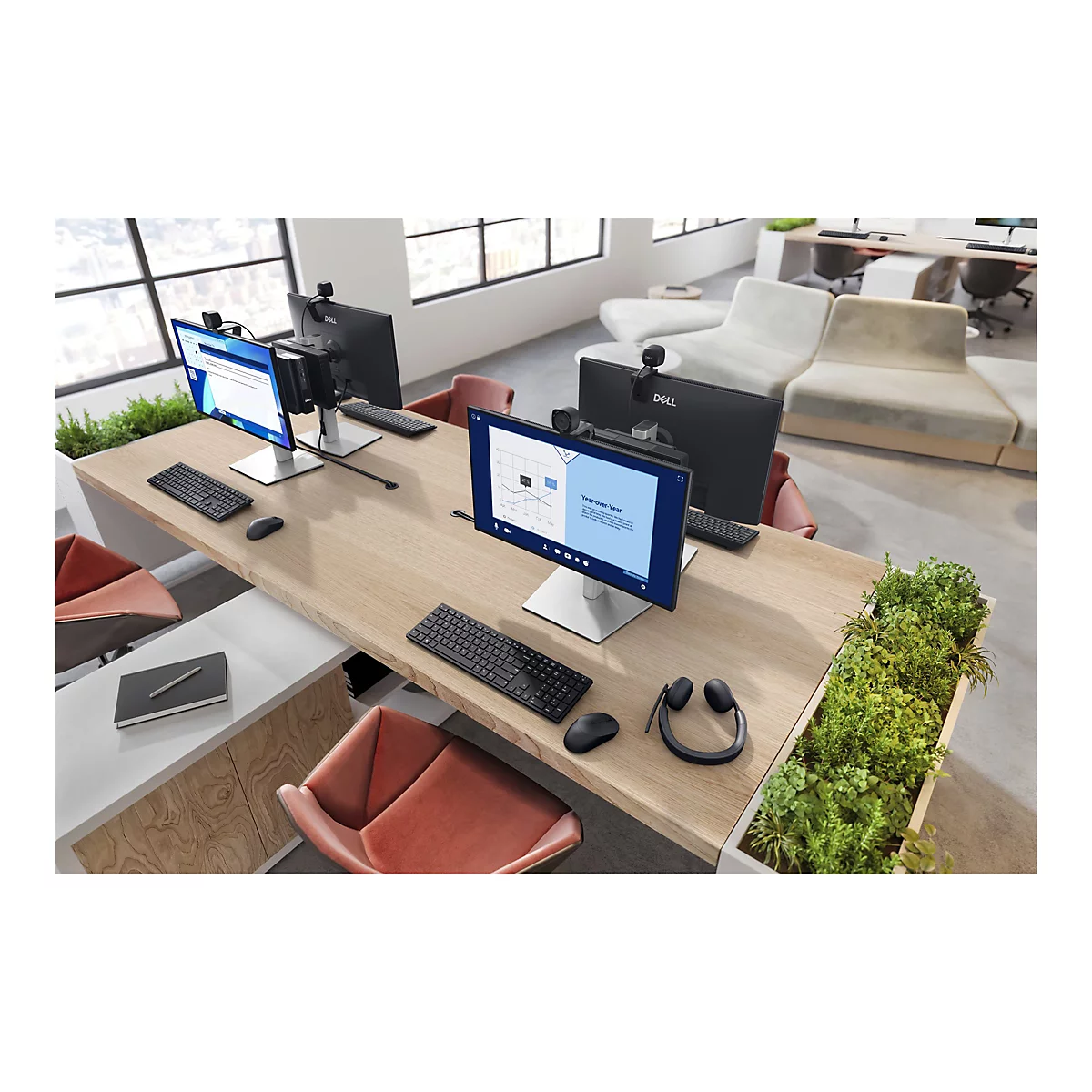 Une configuration de bureau comprenant des moniteurs, des webcams, des claviers et des casques sur une table en bois, avec des plantes ornant l'espace.