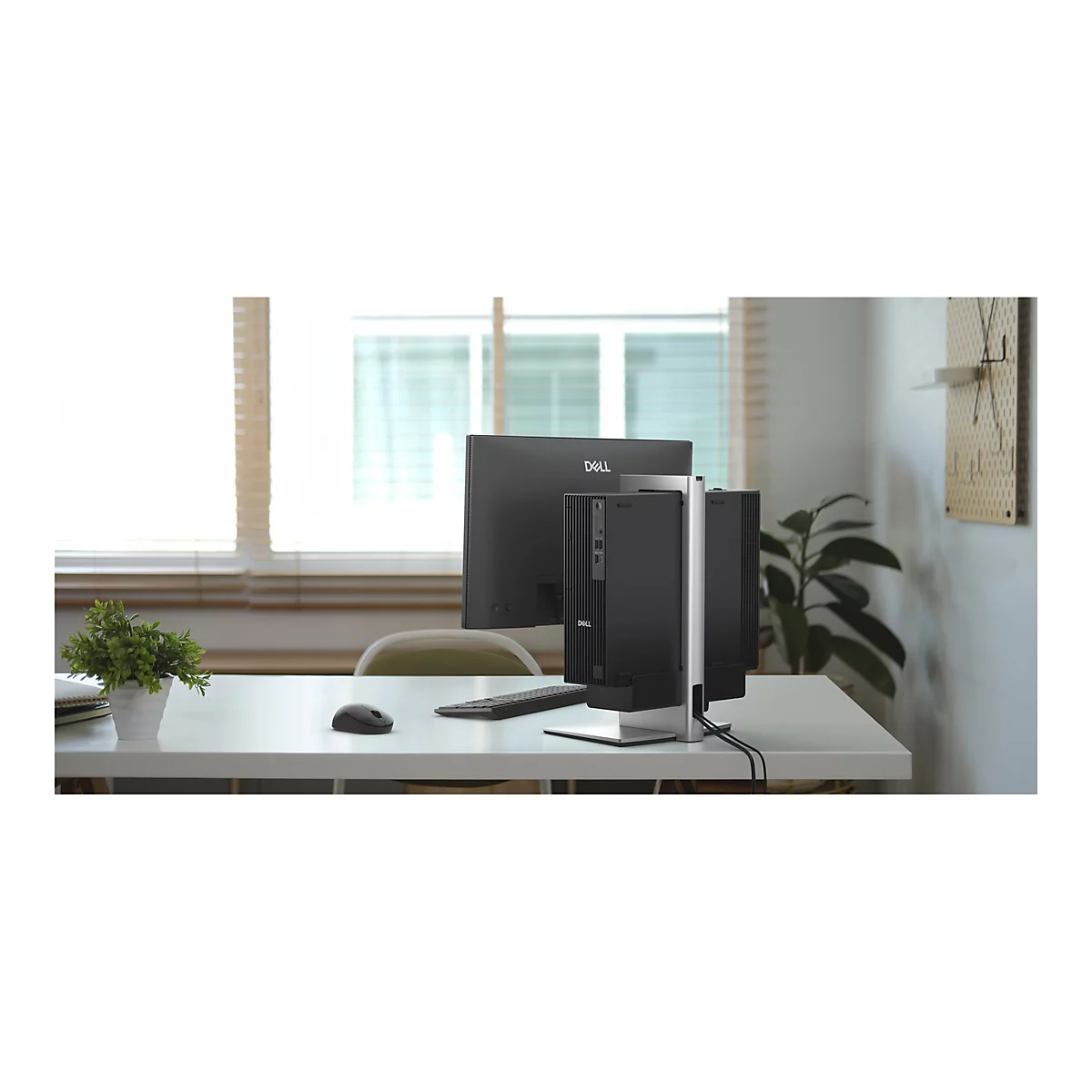 Schreibtisch mit Dell-Monitor, PC-Gehäuse und Zubehör. Fenster und Wand mit Dekoration im Hintergrund.