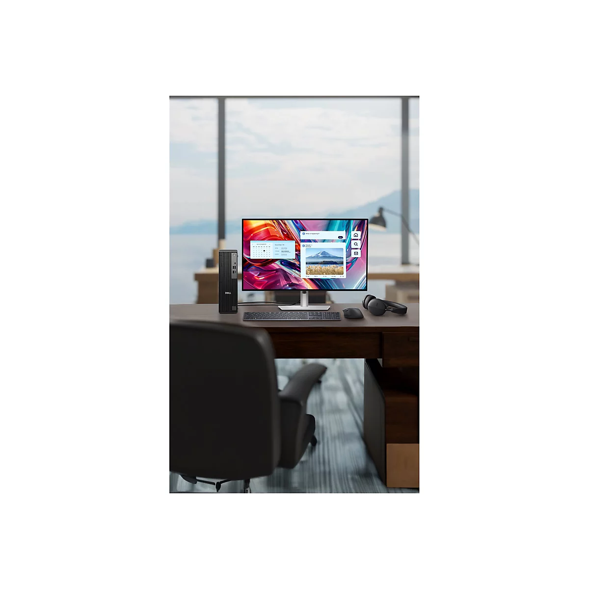Schreibtisch mit Computer, Monitor, Tastatur, Maus, Kopfhörer. Fenster mit Ausblick auf Meer.
