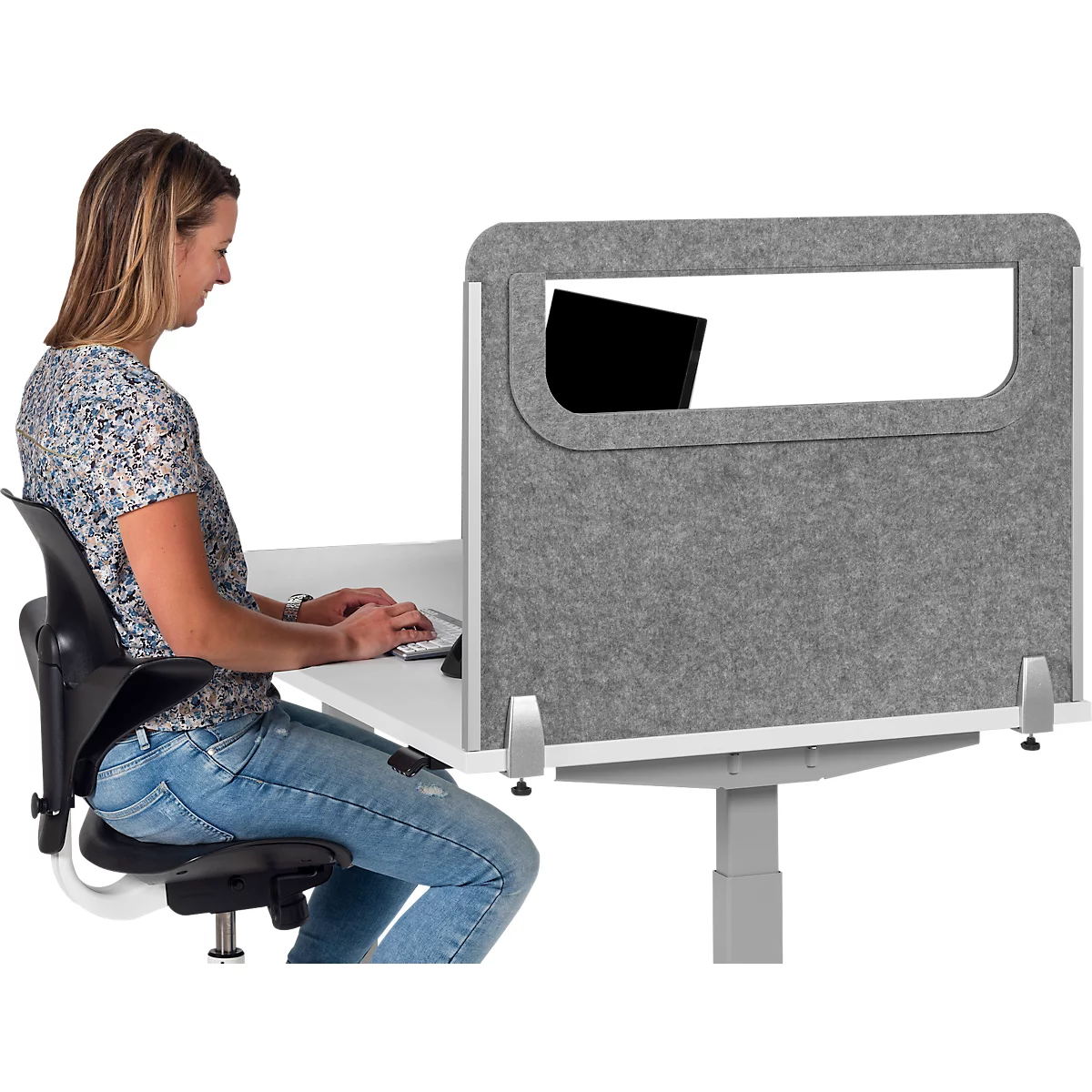 Woman typing at desk. Gray privacy screen with window on table.
