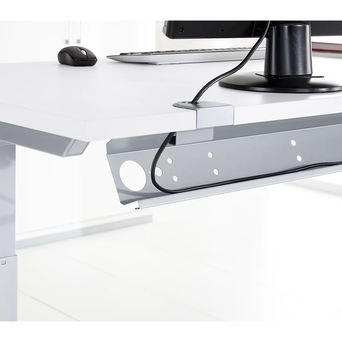 Close-up of a white desk with cable management. Gray cable tray, black cables, mouse, monitor.