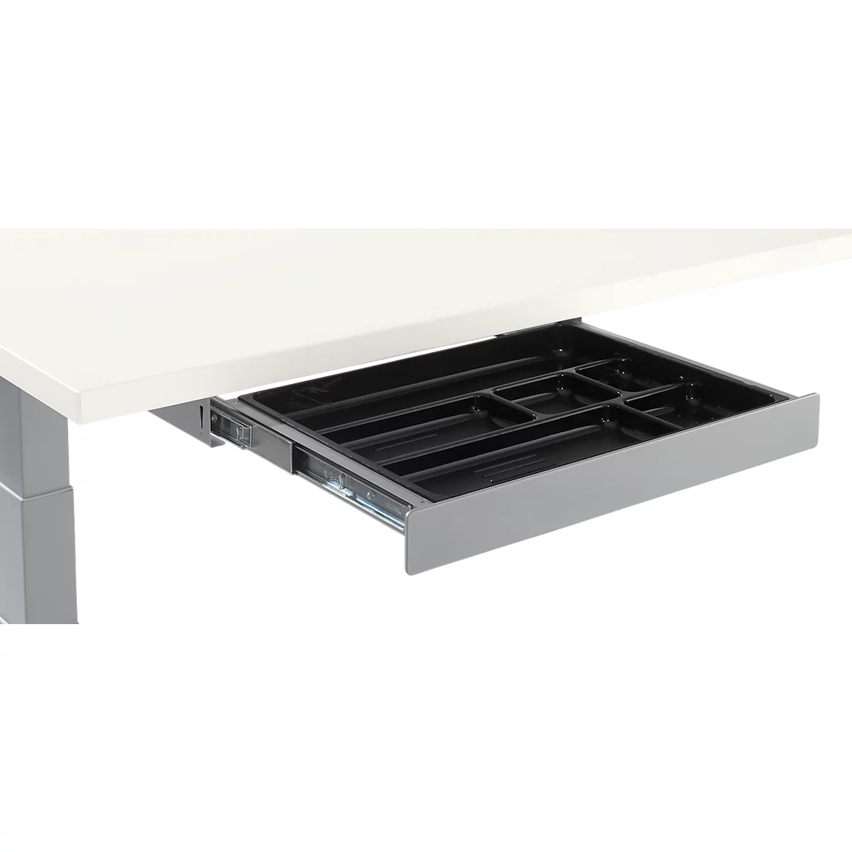 Black plastic pull-out drawer with compartments under a light-colored table top. Gray drawer box.