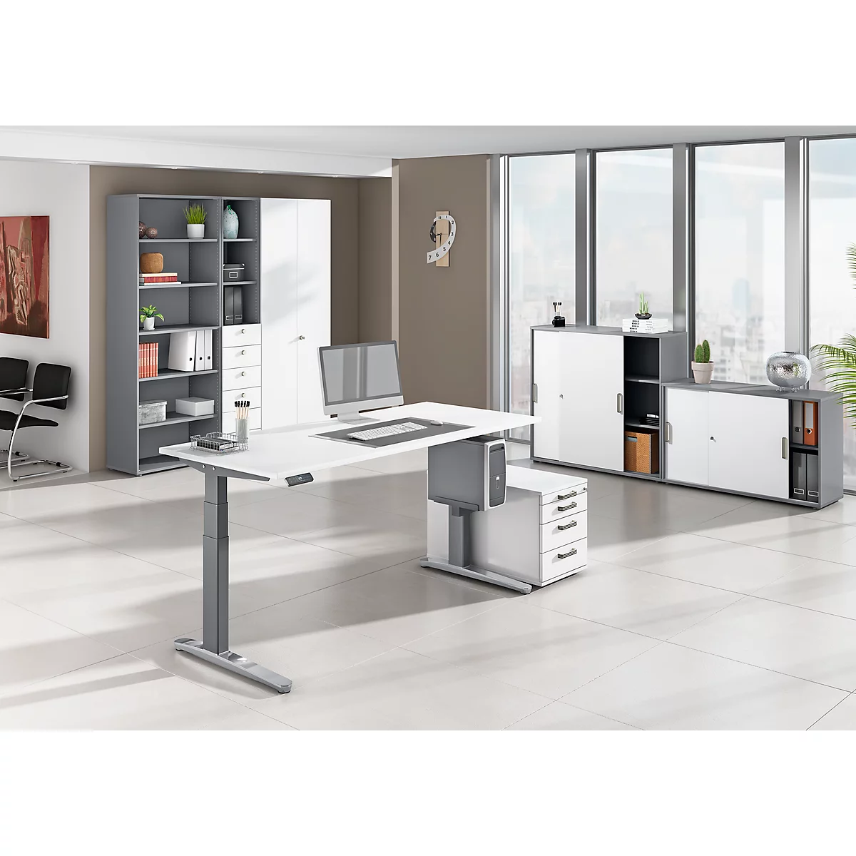 Modern white height-adjustable desk in an office. Cabinets in the background, a window with a view.