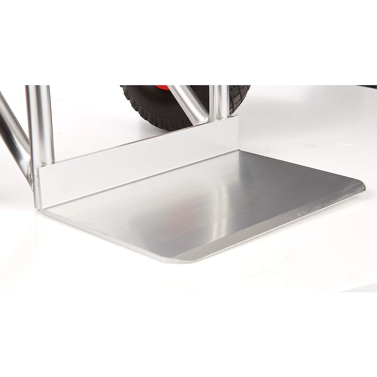 Gros plan d'une plaque en aluminium argenté, faisant partie d'un chariot de transport. Un pneu est visible sur la plaque.