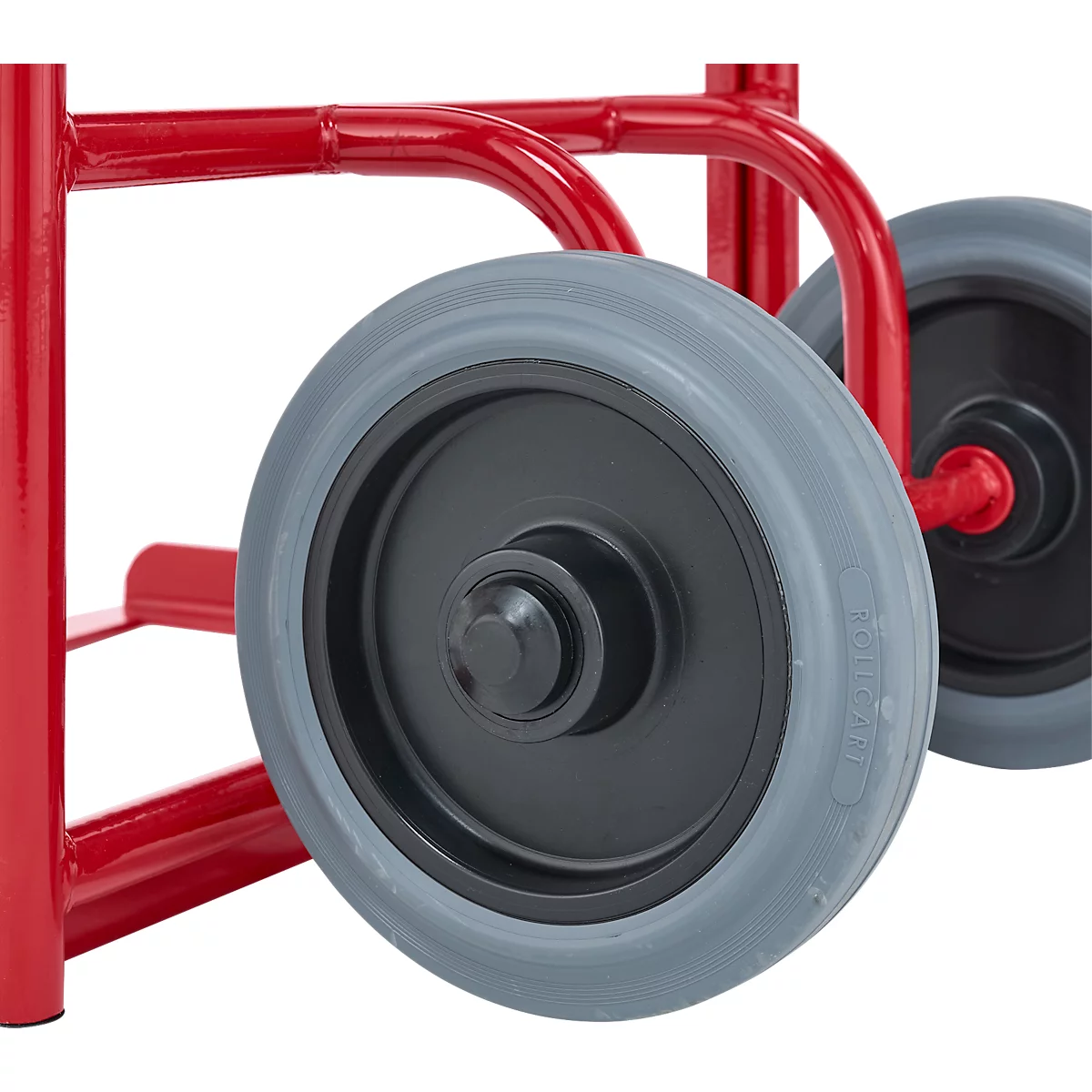 Gros plan sur deux roues grises et un cadre en métal rouge. Les roues sont fixées à une brouette ou à un appareil similaire.