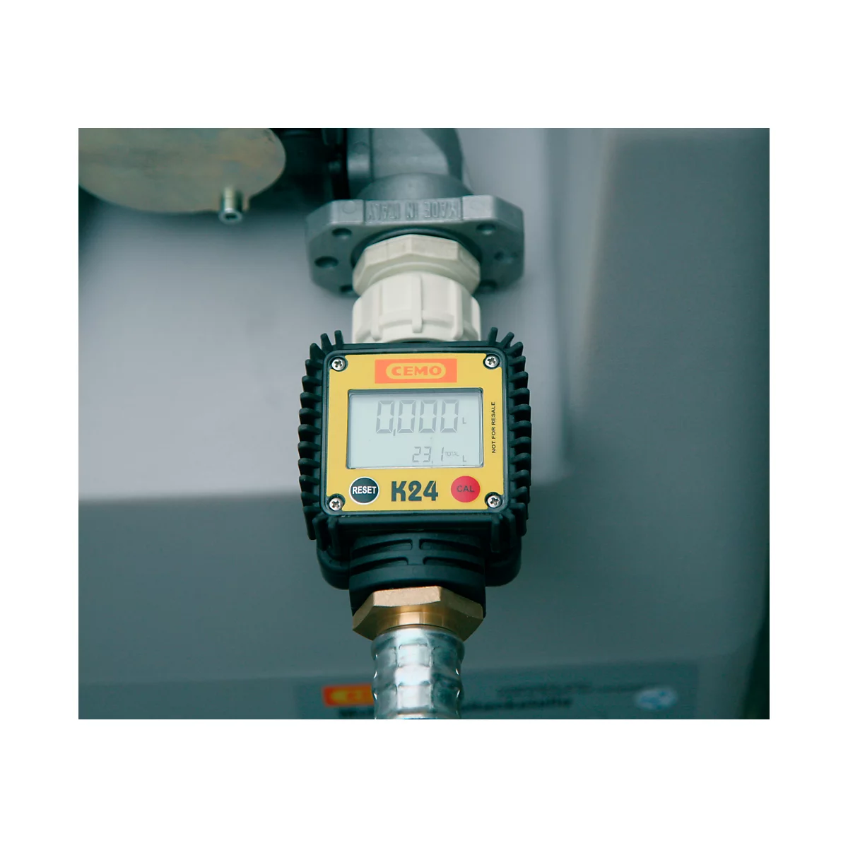 Close-up of a yellow flow meter with digital display: 0.000 and K24. The connection to a metallic part is shown.