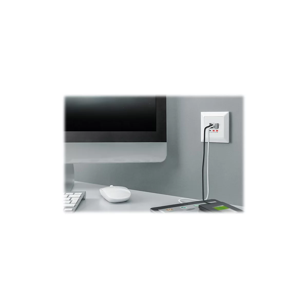 WeiÃŸer Stecker mit schwarzen und weiÃŸen Ladekabeln, die ein Smartphone und Tablet laden. Im Hintergrund ein Monitor und eine Tastatur.