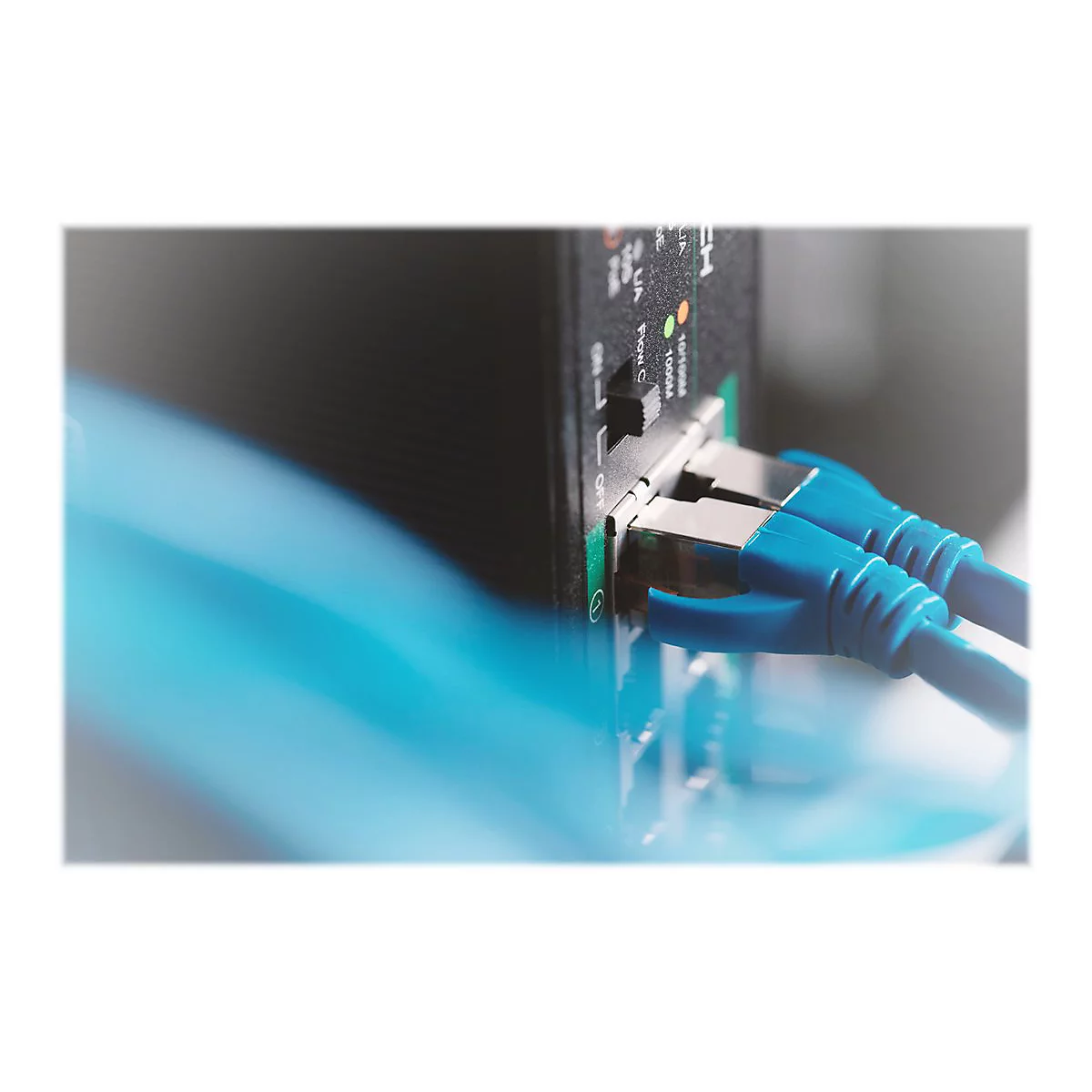 Nahaufnahme eines schwarzen Servers mit eingesteckten blauen Ethernet-Kabeln.