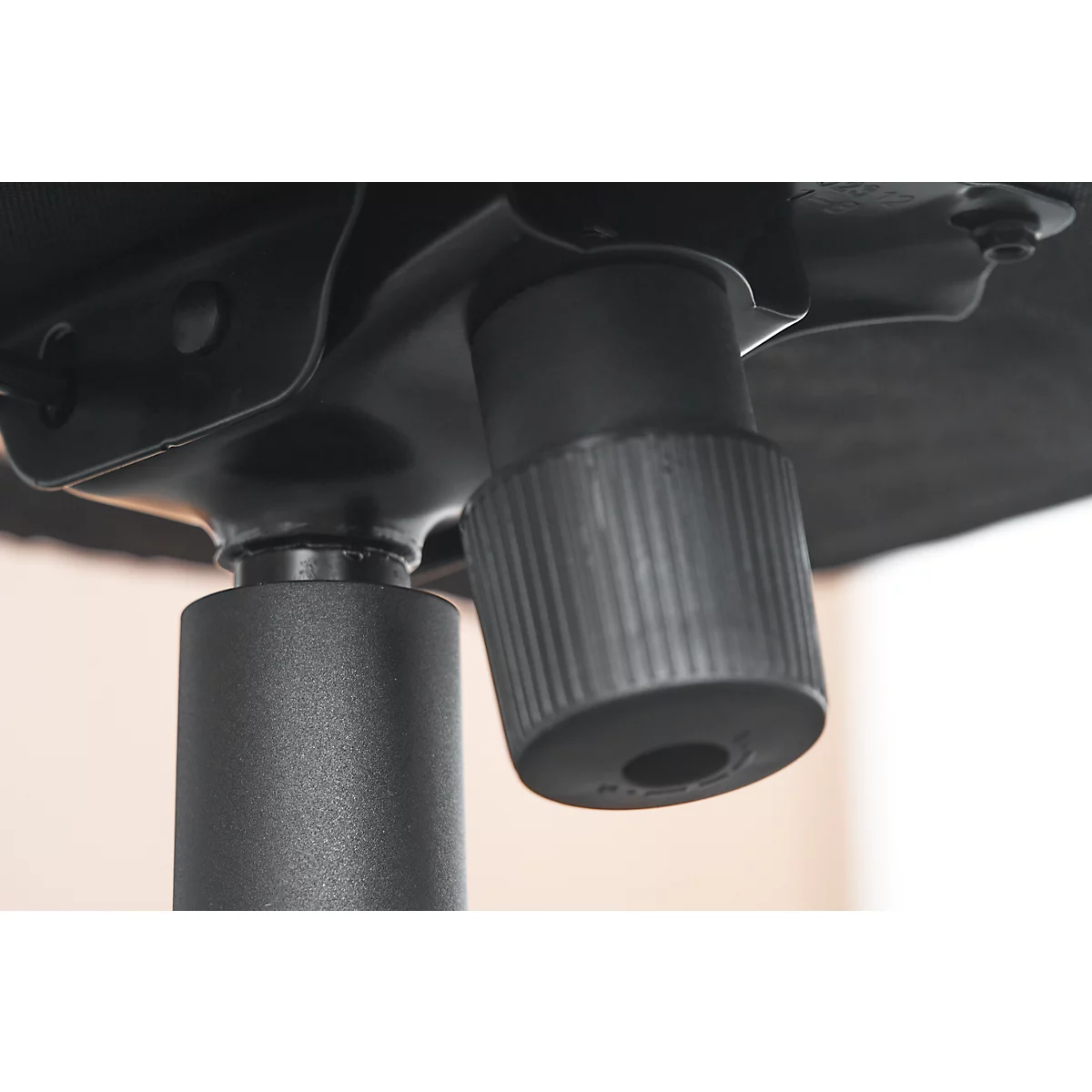 Detailopname van de draaiknop op een bureaustoel. De knop, met ribbels, wordt van opzij bekeken.