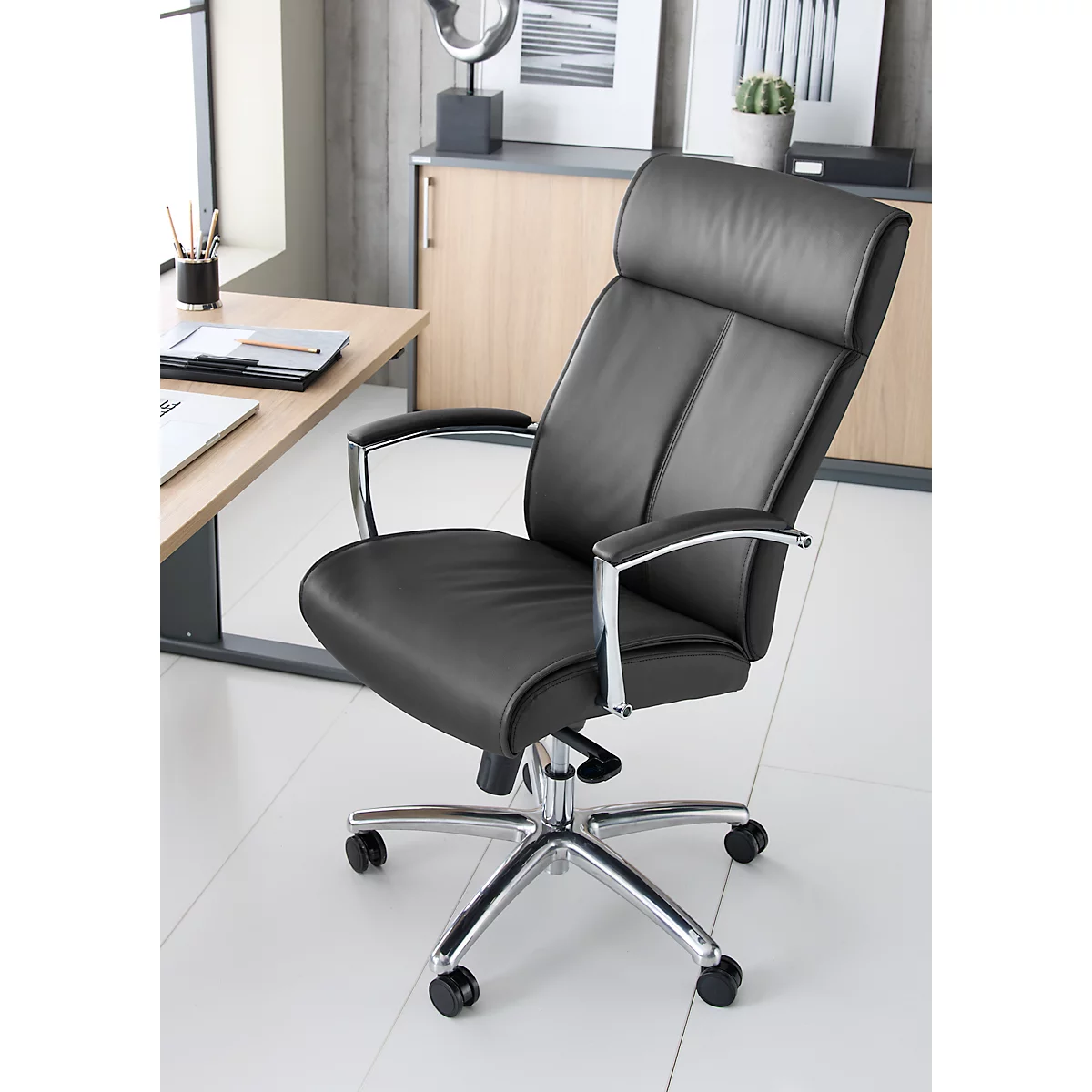 Zwarte bureaustoel met chroom frame staat voor lichte meubels. Details: hoofdsteun, armleuningen, wielen.
