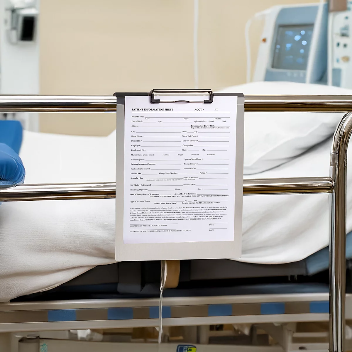Klemmbrett mit Patienteninformationsblatt hängt am Metallgitter eines Krankenhausbetts.