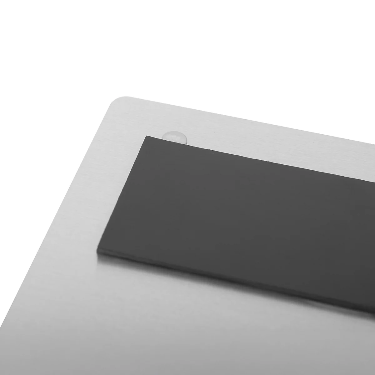 Nahaufnahme einer gebürsteten Metalloberfläche mit einem daran befestigten, rechteckigen schwarzen Magnetstreifen.