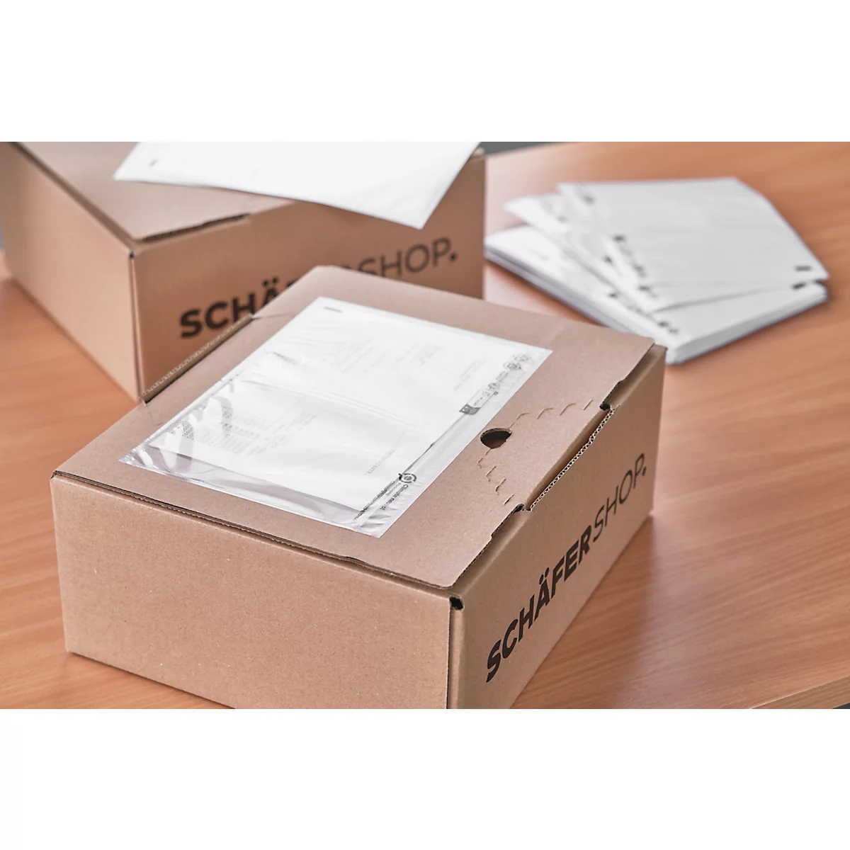 Two brown cardboard boxes with "Schäfer Shop" print and documents lie on a table.