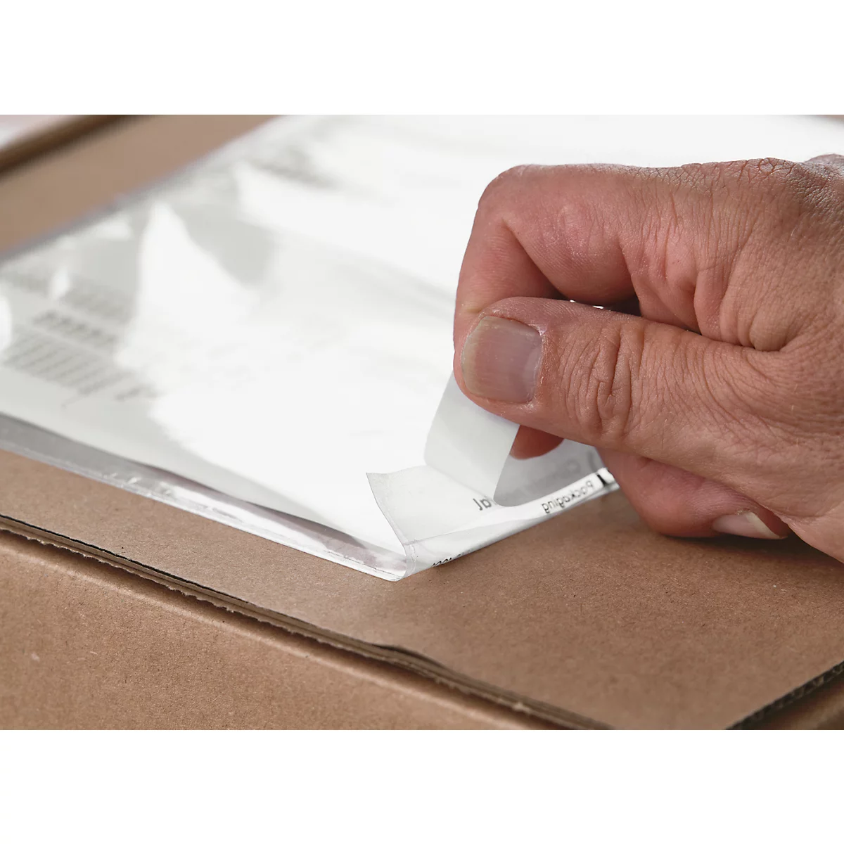 Hand opening transparent plastic bag in a cardboard box containing papers.