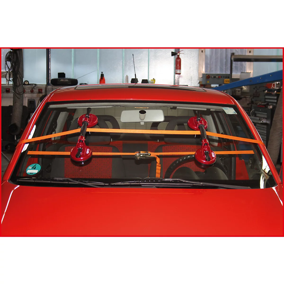 Rotes Auto mit installierten Saughaltern an der Windschutzscheibe. Gelbe Gurte fixieren diese.