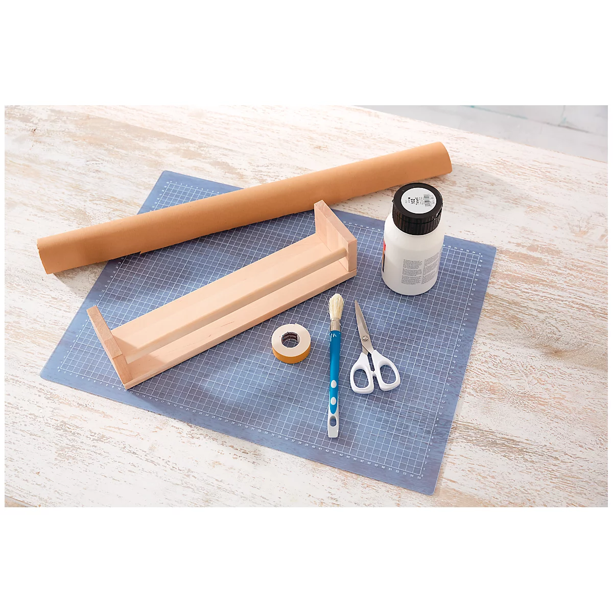 Wooden shelf, glue, paper roll, brush, scissors and tape on a blue surface. For crafts.