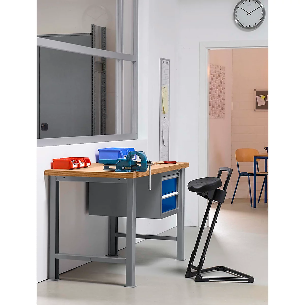 Workbench with vise and accessories. Toolbox and chair. Clock on the wall.