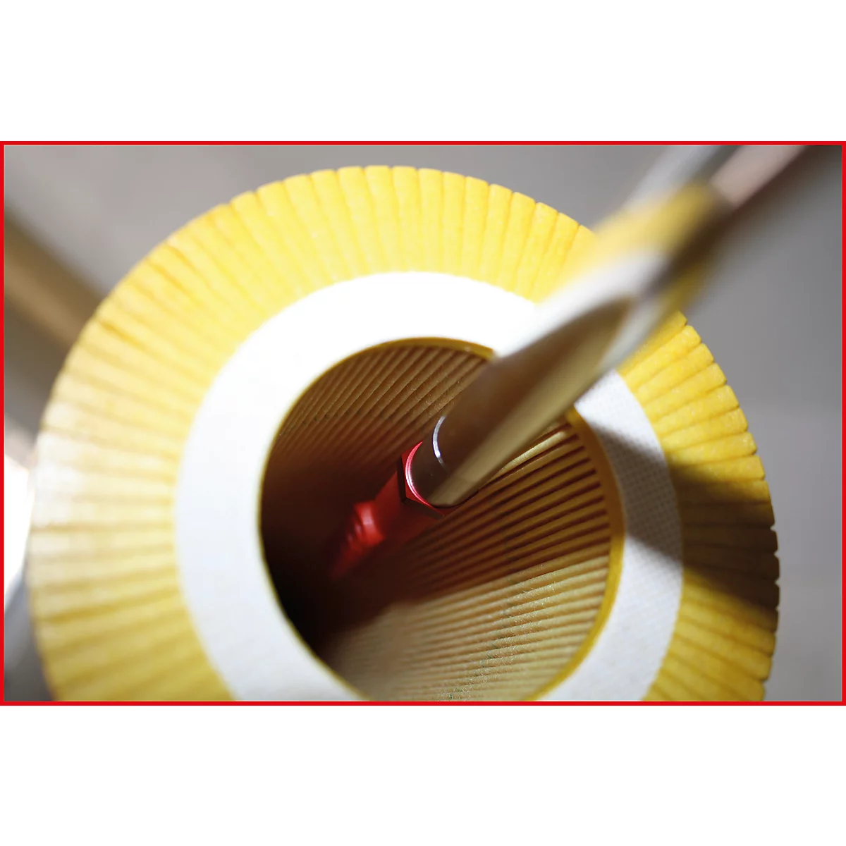 Nahaufnahme eines gelben Papierfilters mit einer Stange, die in ein rotes Loch eingeführt wird.