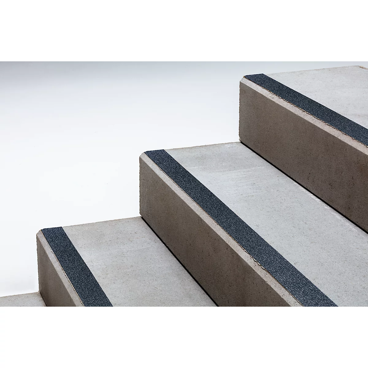 Grey stone steps with non-slip black strips on the edges.