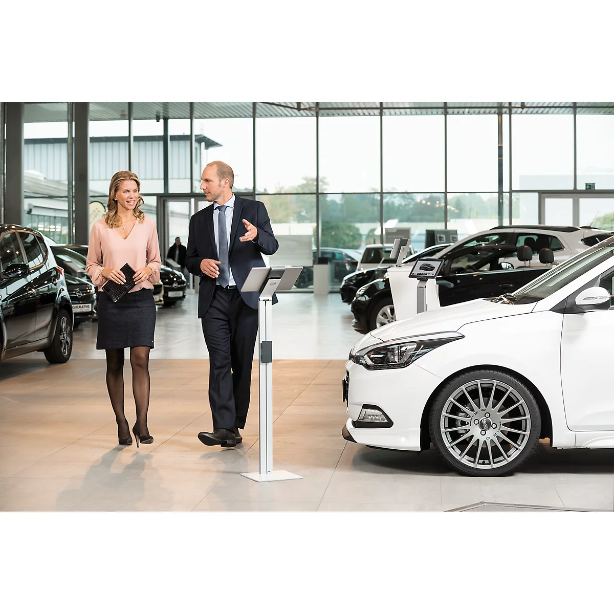 A car salesman in a conversation with a customer in a bright showroom.