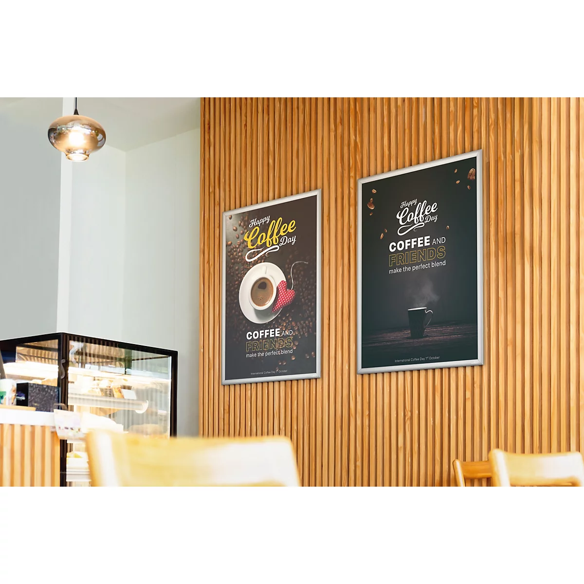 Twee ingelijste posters met koffiemotieven hangen aan een wand van verticale houten latten in een café.
