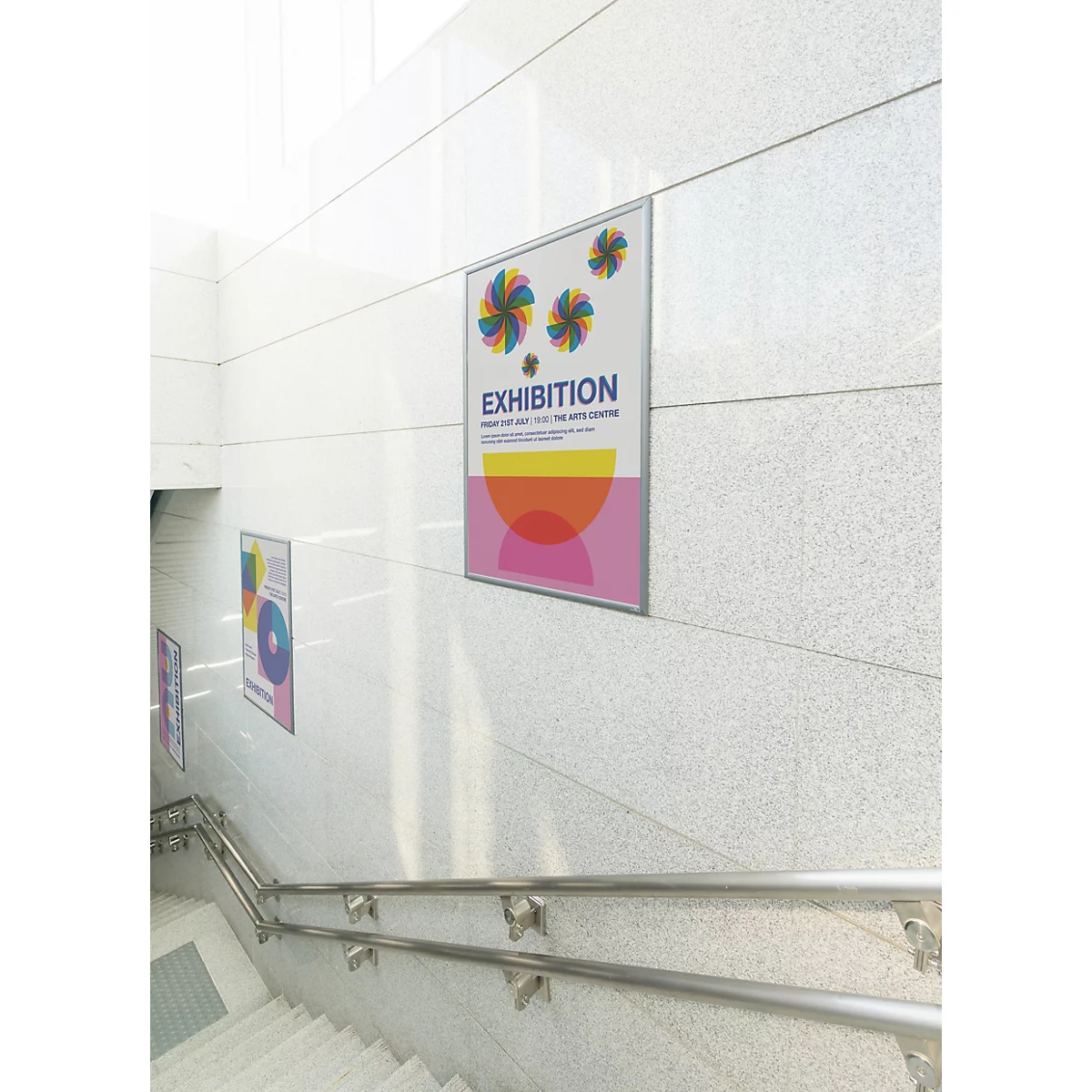 Tentoonstellingsposter met kleurrijke cirkels op een lichte marmeren trapmuur.