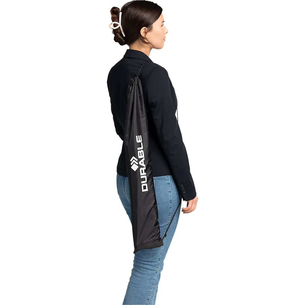 A woman wearing a black blazer and jeans carries a black bag with the word DURABLE on it.