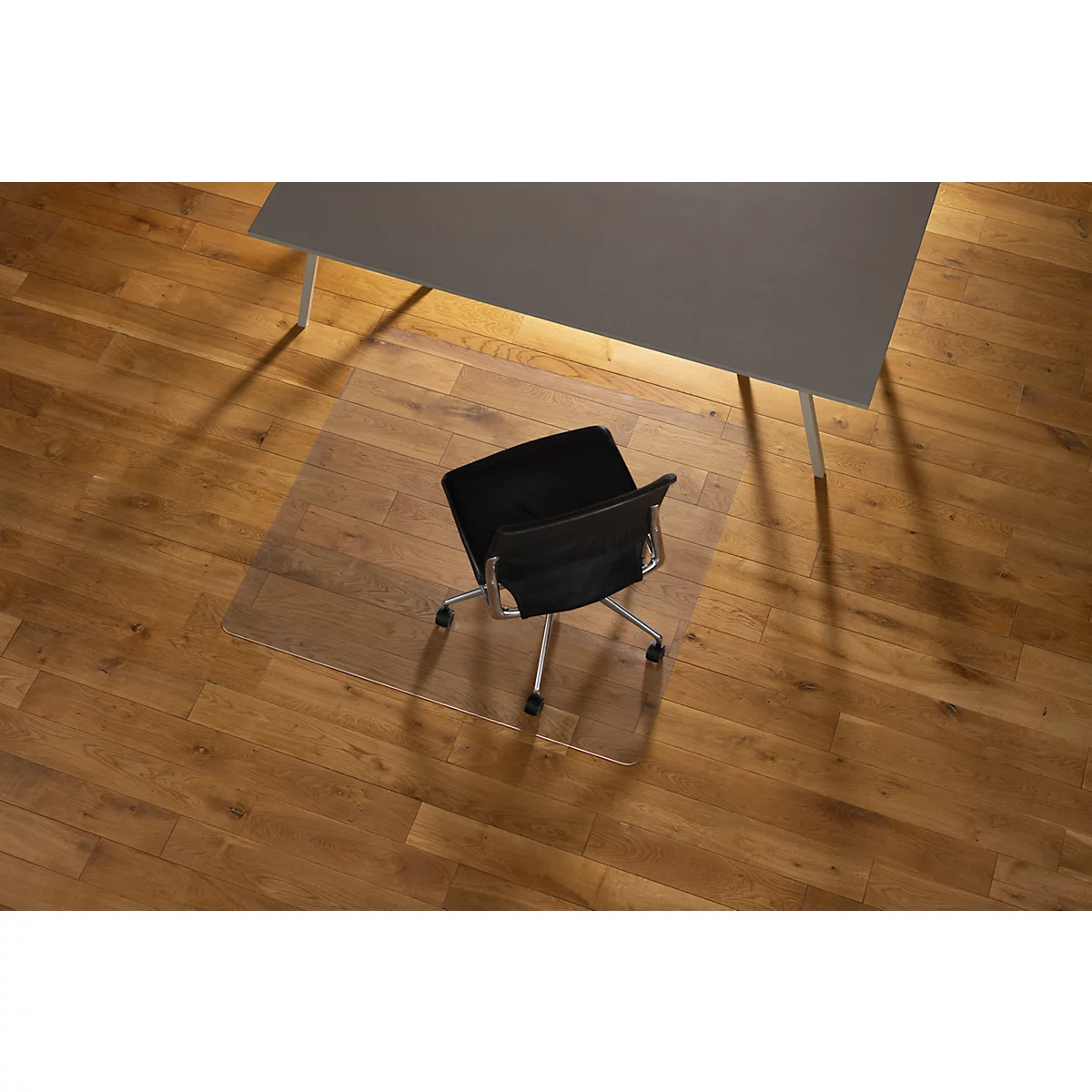 Silla de oficina sobre alfombra protectora de suelo transparente sobre suelo de parquet.