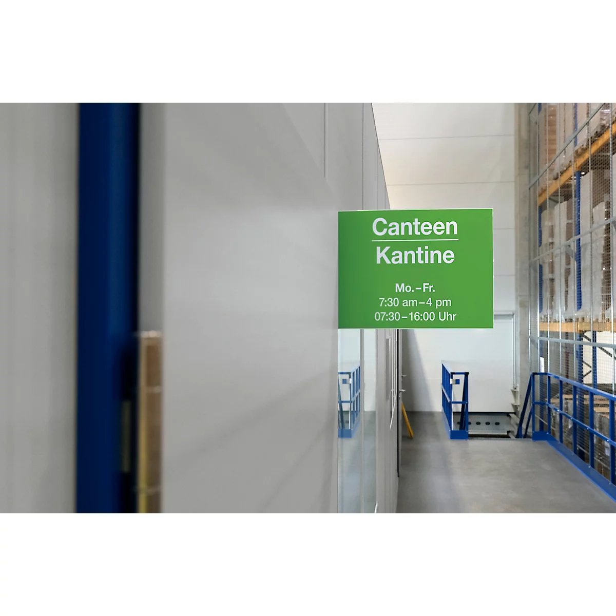 Groen kantinebord met witte tekst op een witte muur. Openingstijden staan vermeld.