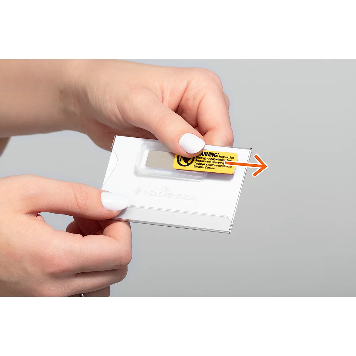 Handen houden een witte verpakking met een geel waarschuwingslabel. Een oranje pijl geeft de richting van verwijdering aan.