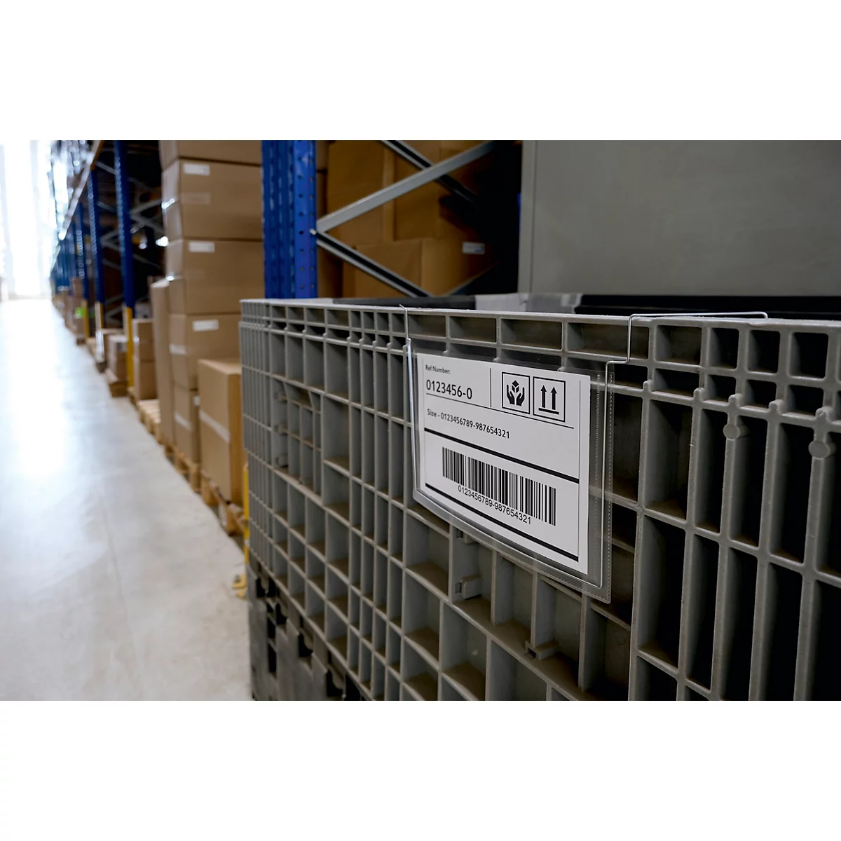 Grijze plastic container met etiket in een magazijn. Op het etiket staat "0123456-0" en een barcode.