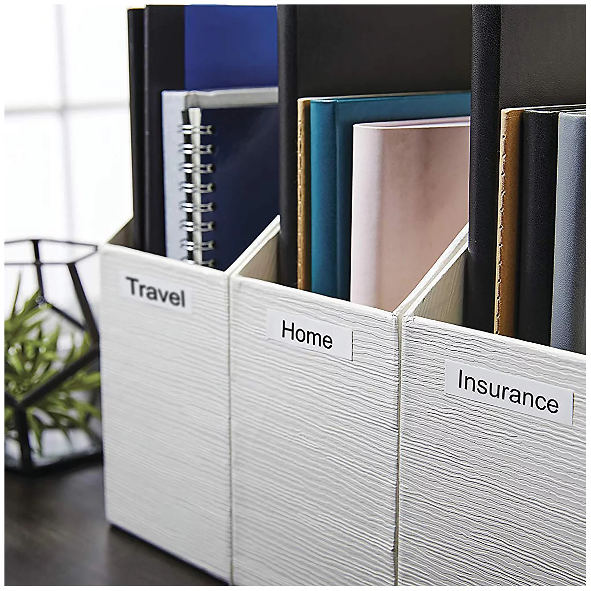 Drei weiße Ordner mit Beschriftungen: Travel, Home, Insurance, gefüllt mit Büchern und Notizbüchern.