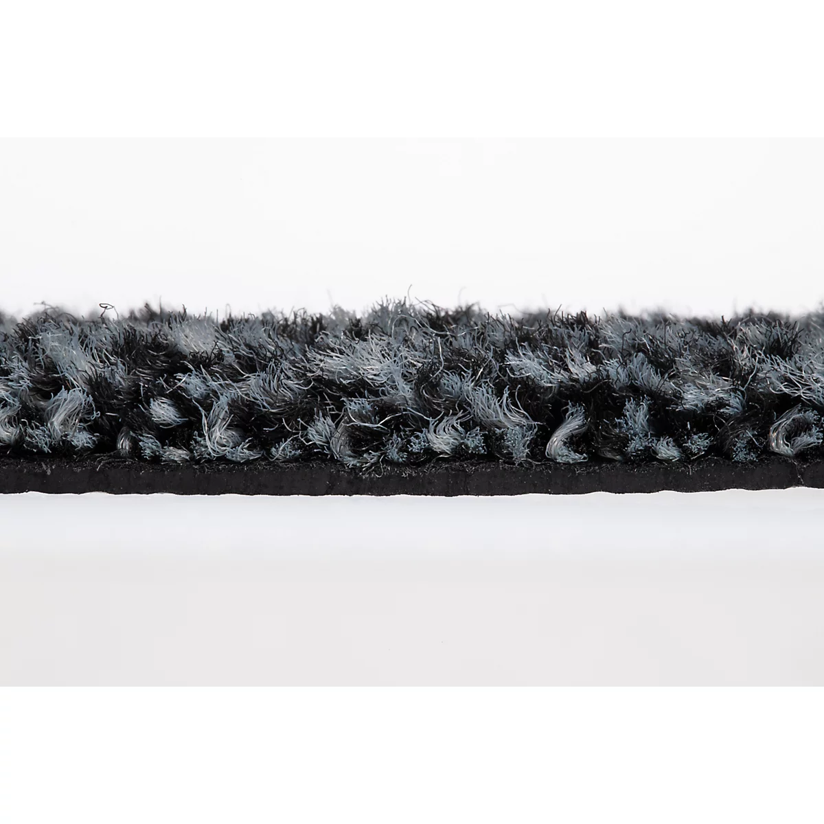Primer plano del borde de una alfombra de pelo largo en tonos negros y grises.