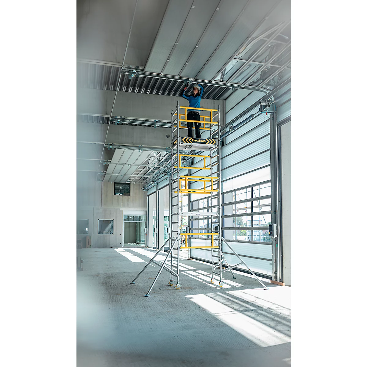 Personne travaillant sur le plafond sur un échafaudage. Chantier avec porte roulante ouverte.