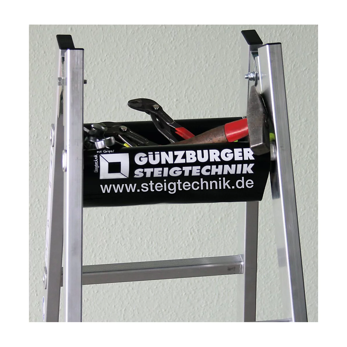 Bac à outils avec marteau, pince et clé sur une échelle. L'impression noire affiche « Günzburger Steigtechnik » et le site Web.