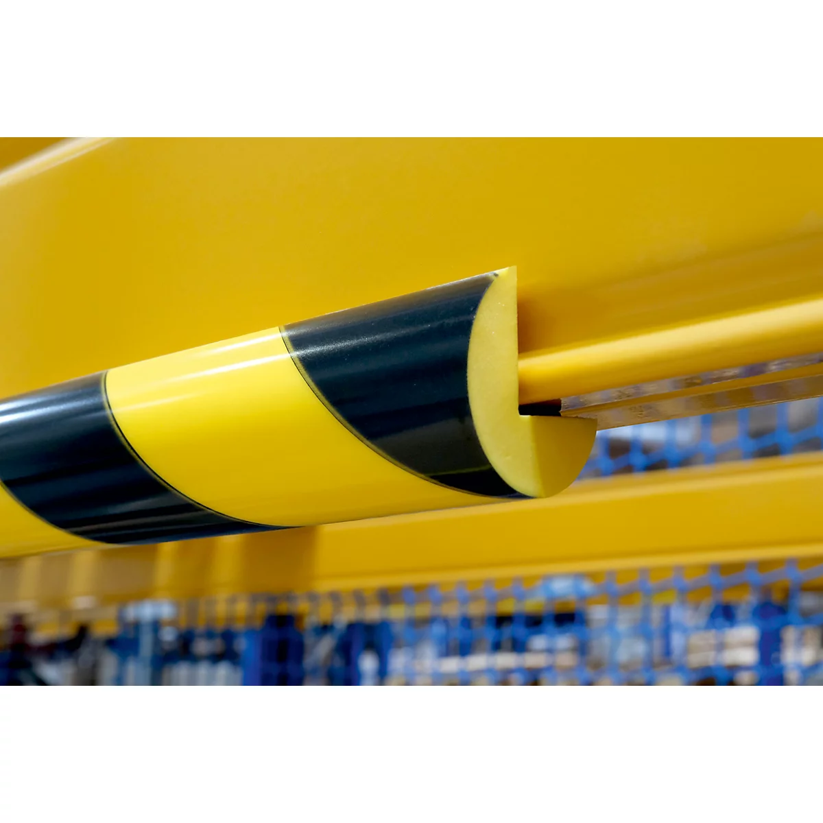 Gelbe Metallstange mit schwarz-gelbem Warnstreifen. Ein Detail aus einer Lagerhalle.