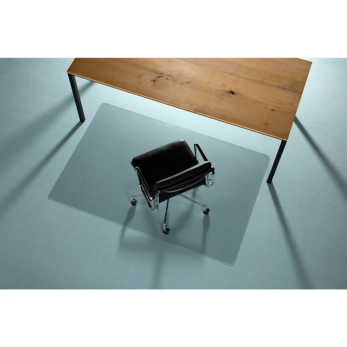 Bureaustoel op transparante vloerbeschermingsmat onder houten tafel.