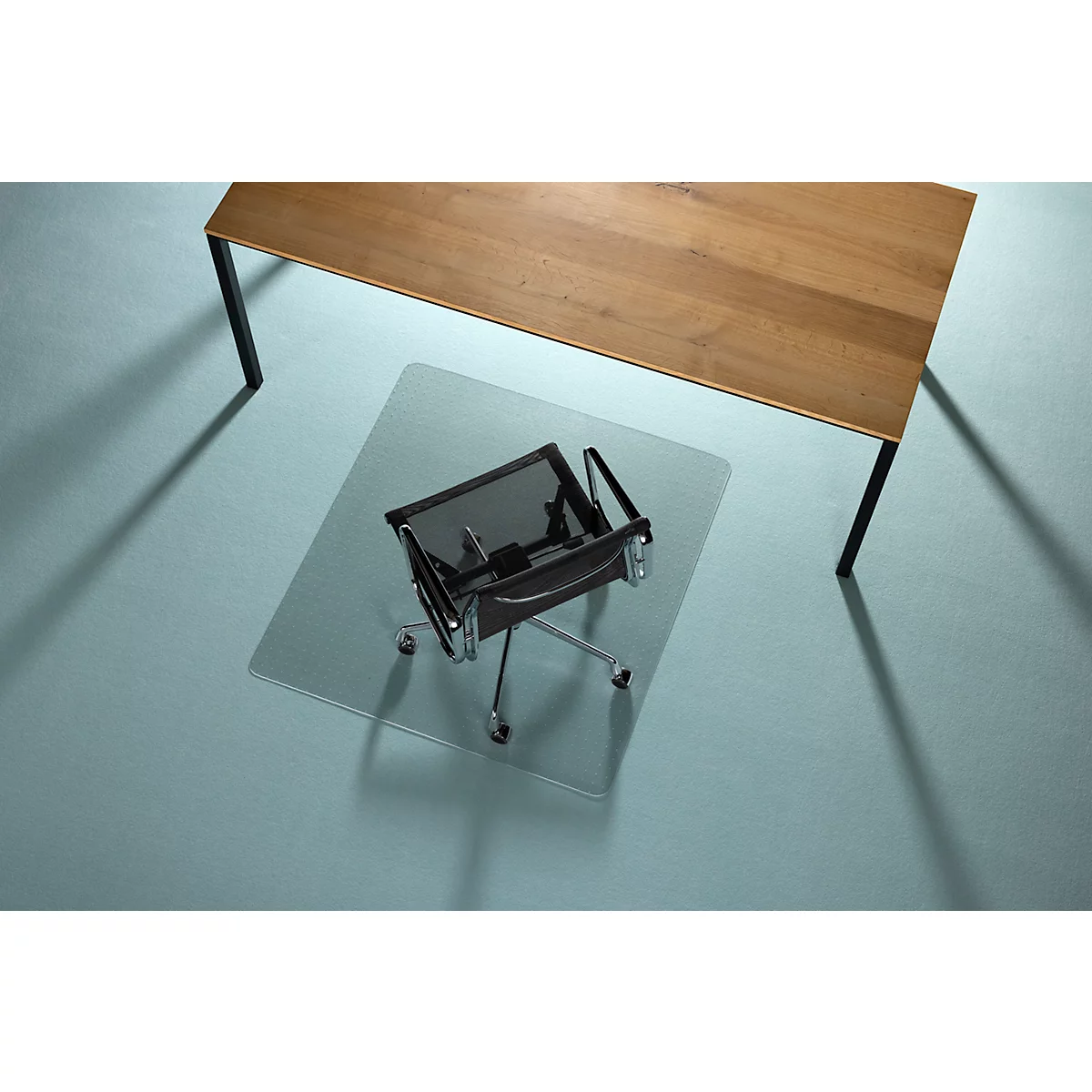 Bureaustoel op transparante vloerbeschermingsmat onder houten tafel. Blauw oppervlak.