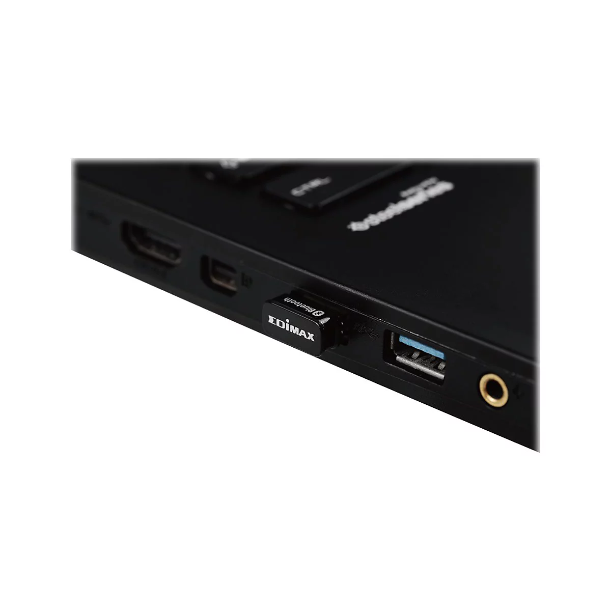 Ein kleiner Edimax Bluetooth-Adapter steckt in einem USB-Anschluss an der Seite eines schwarzen Laptops.