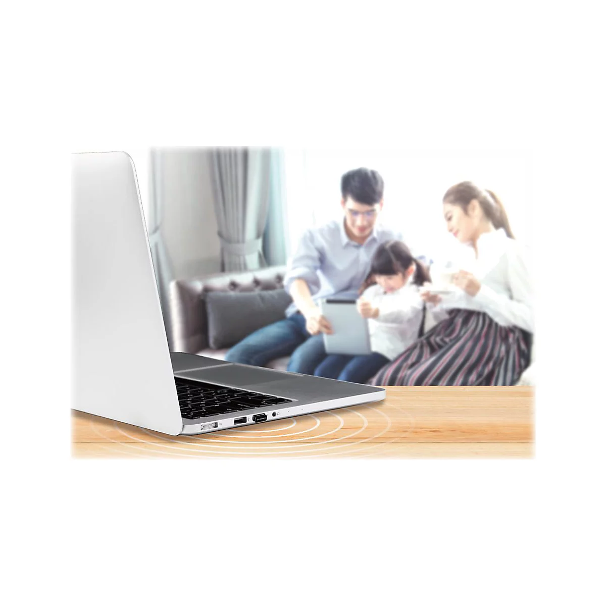 Ein Laptop im Vordergrund. Im Hintergrund sitzt eine Familie auf dem Sofa und benutzt ein Tablet.