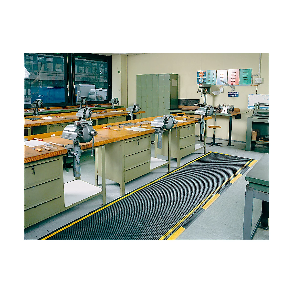 Workshop with workbenches, vices, and machines. Black flooring with yellow stripes.