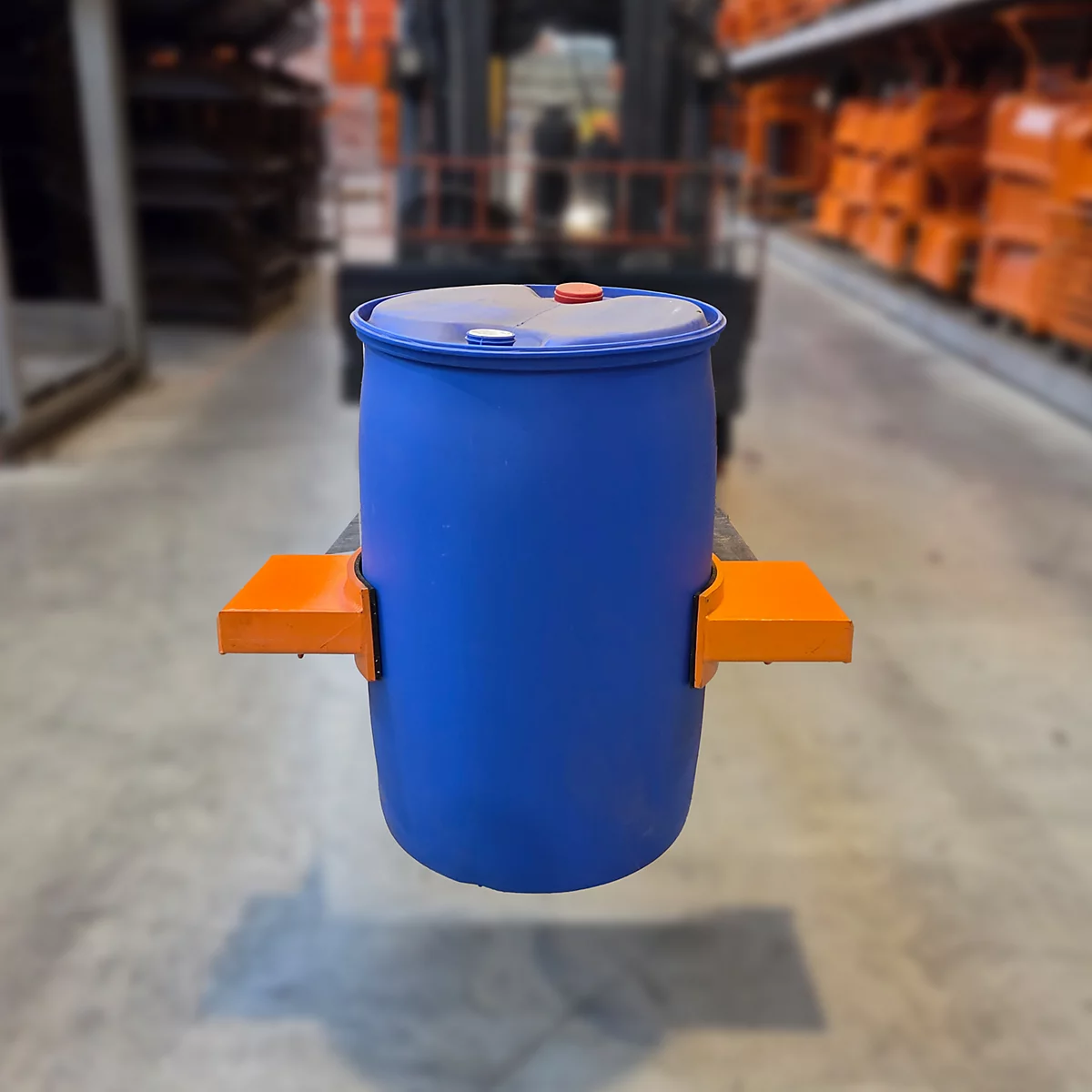 Blauer Fassheber, mit orangefarbenen Halterungen, in einer Lagerhalle auf einem Gabelstapler transportiert.