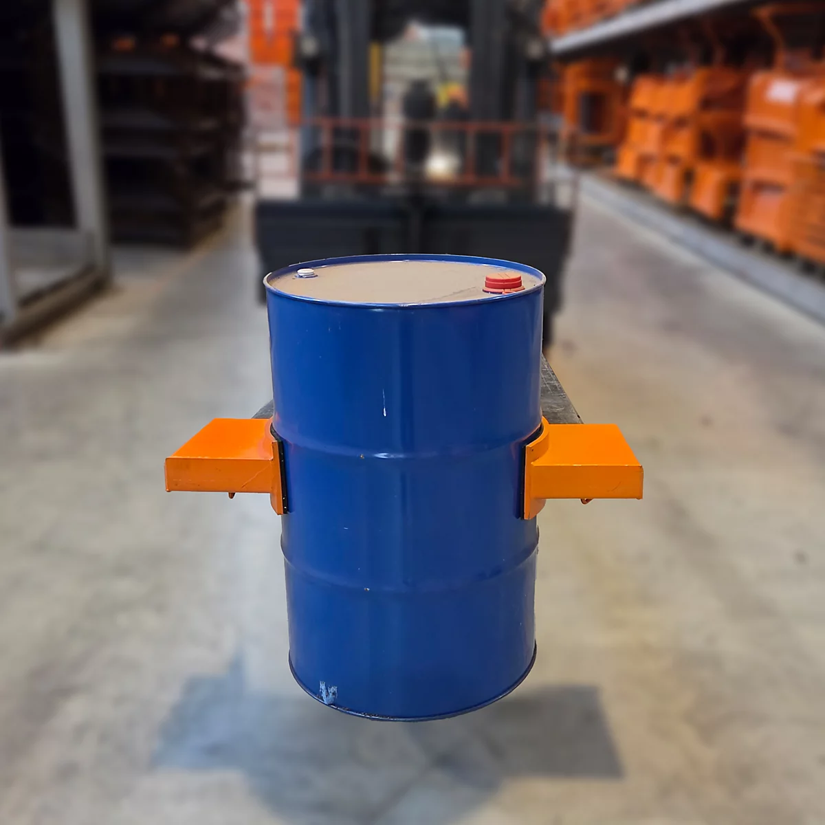 Blauer Metallfass, in orangefarbener Halterung, auf einem Gabelstapler. Lagerhalle im Hintergrund.