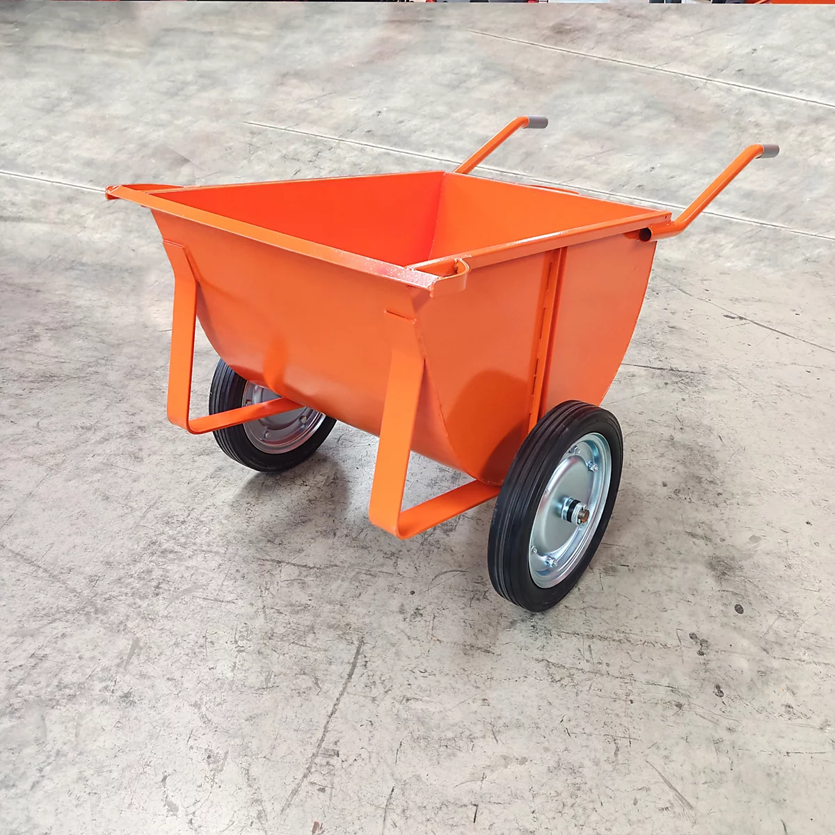 Eine orangefarbene Schubkarre mit zwei Rädern, Metallrahmen und Griffen, vor einem grauen Hintergrund.