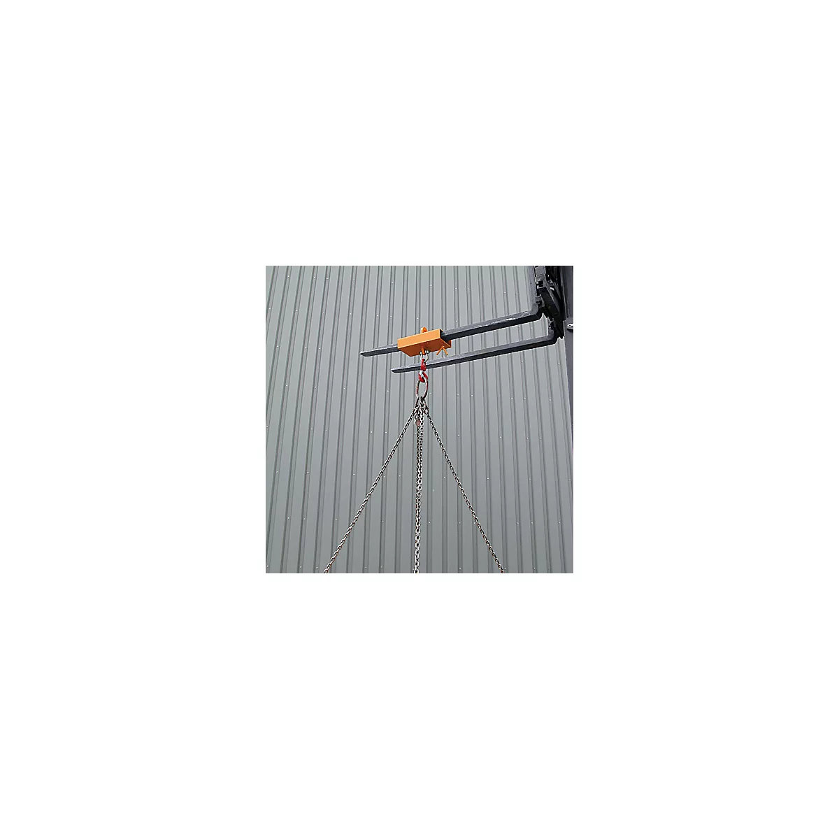Gabelstapler-Lastarm in Orange an Gabelzinken montiert, daran hängen schwere Metallketten vor grauer Wand.