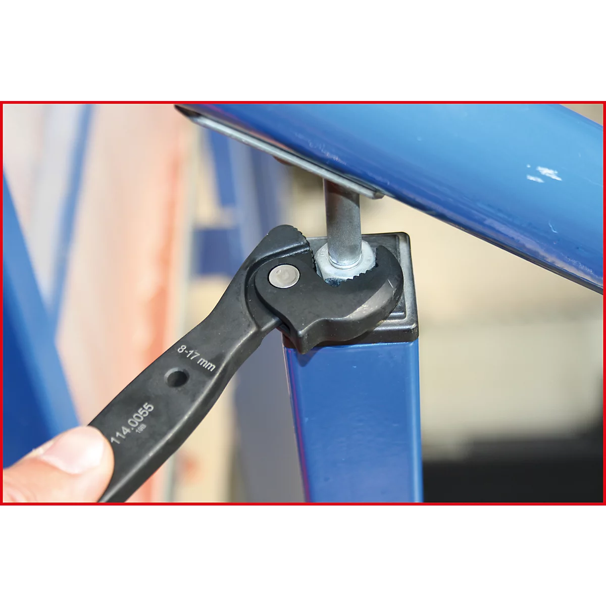 Ein Schraubenschlüssel wird an einem blauen Metallpfosten verwendet. Auf dem Schlüssel steht "8-17 mm" und "114.0055".