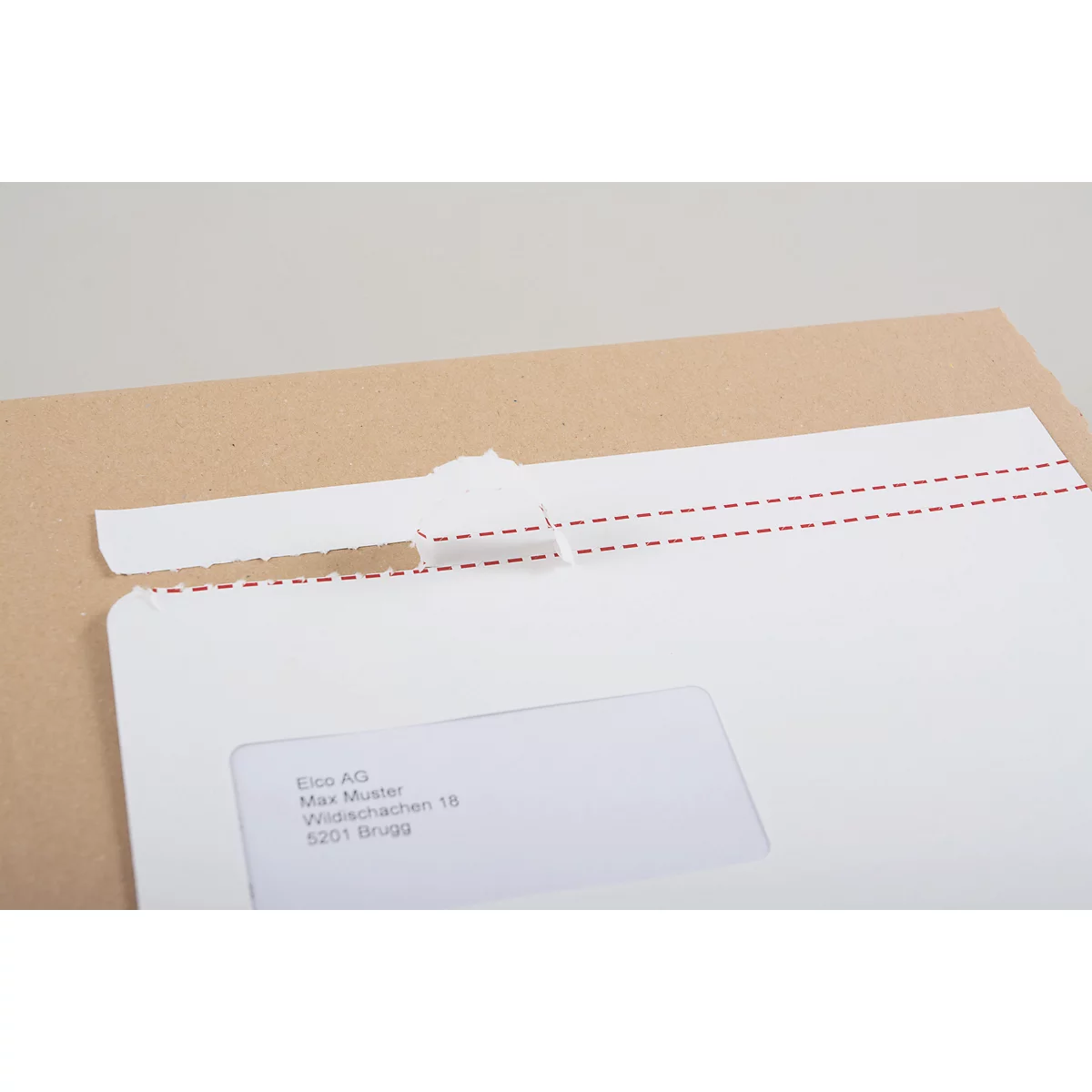 Nahaufnahme eines Briefumschlags, der geöffnet wird. Die Lasche ist eingerissen. Firmenadresse sichtbar.